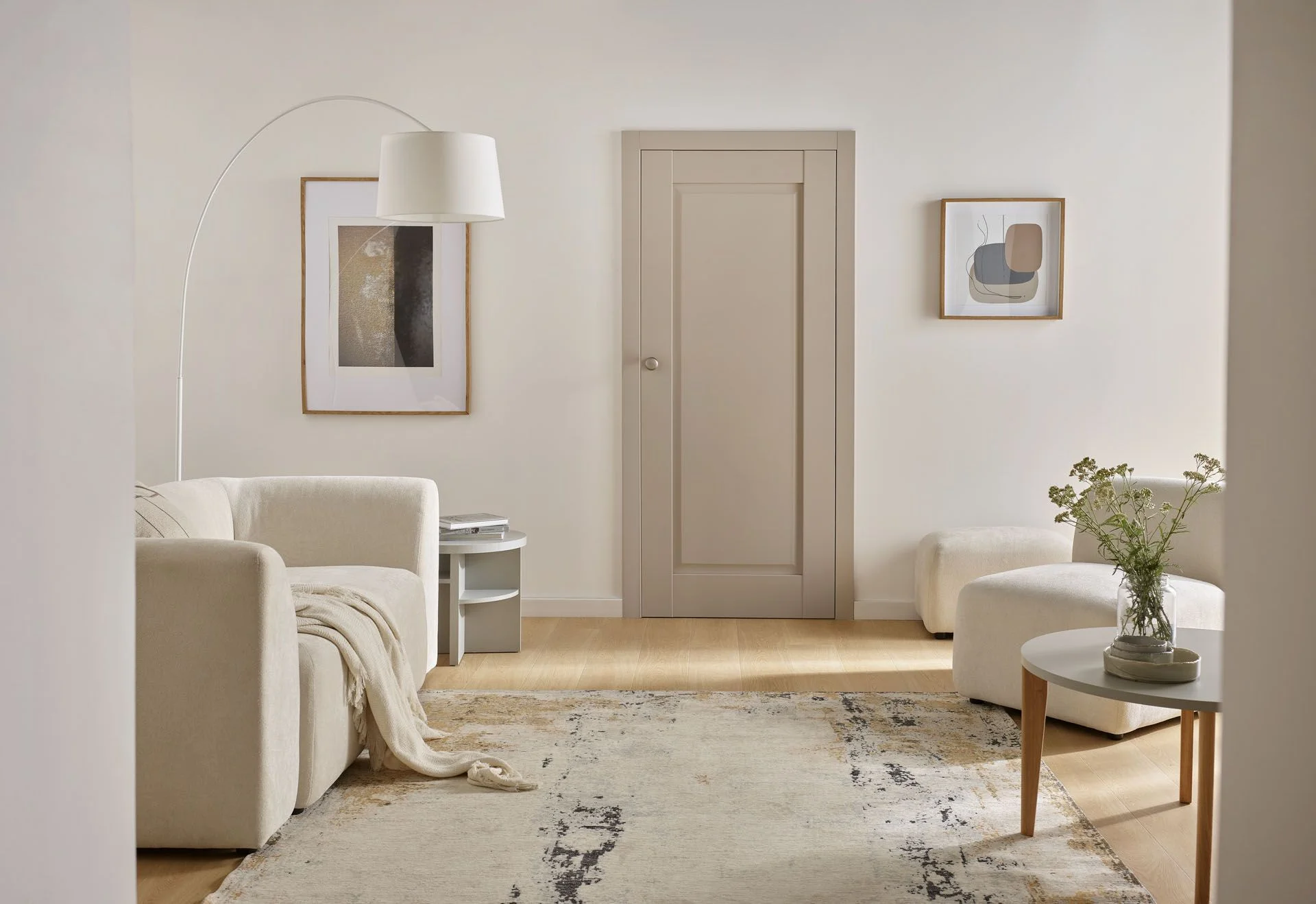 Jasnobeżowe drzwi o klasycznej formie w przytulnym salonie utrzymanym w tonacji off-white.